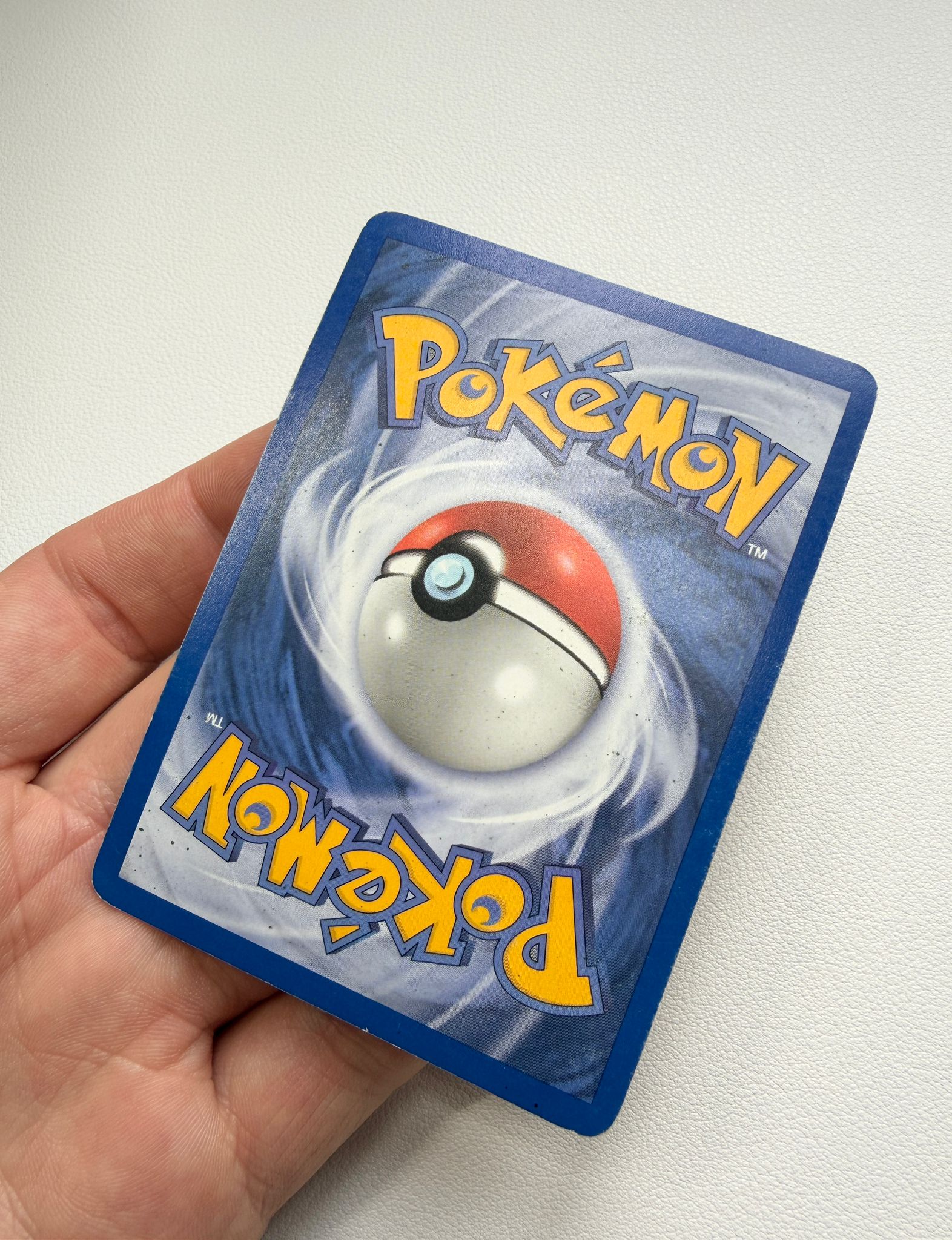 Pokémon trading card back before surface cleaning, showing surface dirt and marks